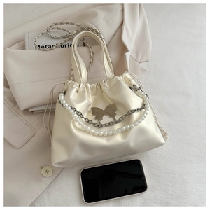 Detail of cream satin bucket bag with pearl chain and metallic butterfly charm