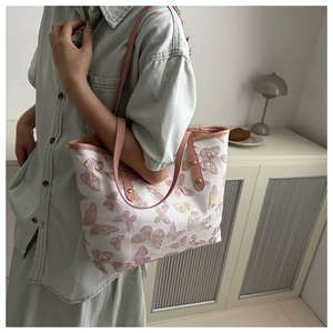 Close-up of pink leather handles and embroidered butterfly pattern on a tote bag