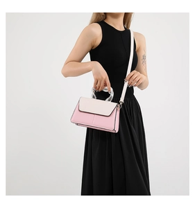 Detail view of pink and beige crossbody bag featuring modern clear acrylic handles