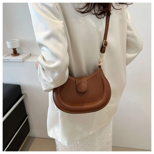Detailed view of the brown leather saddle bag with adjustable strap worn by a model
