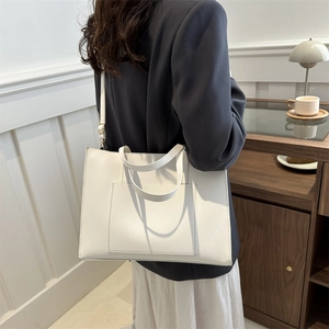 Minimalist white leather tote bag with front pocket and adjustable shoulder strap