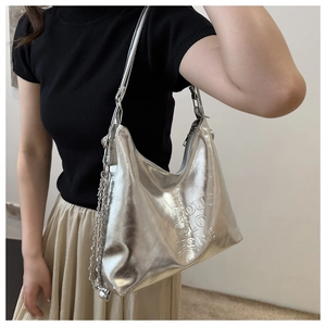 Close-up of silver tote bag with embossed lettering and metal chain strap detail