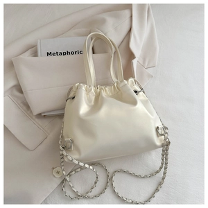 Detailed view of the drawstring closure and pearl luster texture on the beige bucket bag