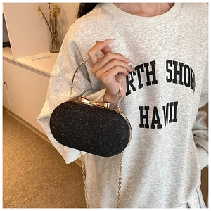 Détail de pochette de soirée à paillettes noires avec poignée dorée et fermoir nœud