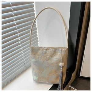 Détail du sac seau en damas cyan clair avec motif jacquard doré et gland violet élégant