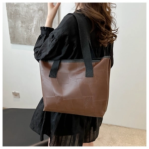 Brown patchwork PU leather tote bag with thick strap shown on a model's shoulder