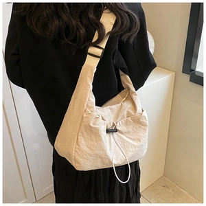 Detail of adjustable nylon strap and drawstring texture on beige crossbody bag