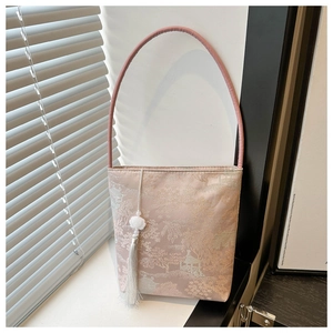Vue détaillée du sac seau en jacquard rose avec motif paysage et pompon blanc