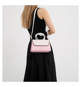 Detail showing contrast color crossbody bag with silver liquid-metal handle worn by a model