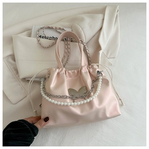 Detail of light pink bucket bag with butterfly accent and elegant pearl handle