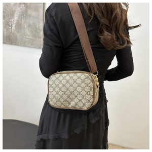 Détail d'un sac bandoulière beige à motif trèfle et large sangle en toile marron