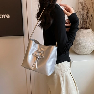 Minimalist silver metallic underarm shoulder bag with ribbon bow worn by model