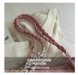 Detail eines rosa geflochtenen Ledergriffs mit dekorativem Seidenschal an der Handtasche