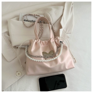 Close-up of pink drawstring bucket bag with silver butterfly and pearl chain strap