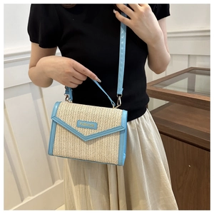 Fashion woven handbag detail with sky blue leather trim and top handle worn by model