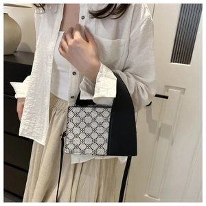 Nahaufnahme von geometrischem Jacquard und schwarzen Ledernähten an einer kleinen Box-Tasche