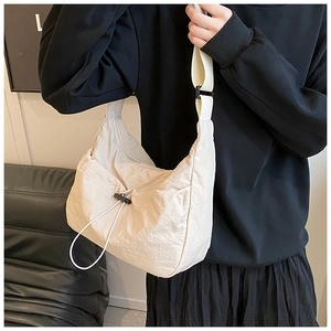 Detail of beige drawstring canvas shoulder bag showing wrinkled texture and strap