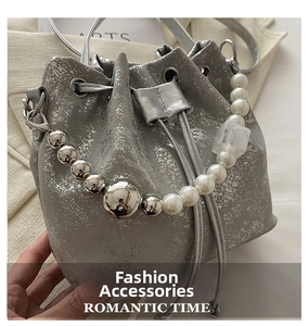 Détail du sac seau métallisé argenté avec poignée en perles et fermeture par cordon