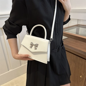 Chic white leather handbag with silver bow detail and shoulder strap for women