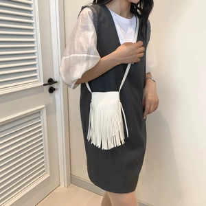 White fringe crossbody bag with long tassels and adjustable strap shown on a model