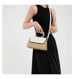 Détail d'un sac bandoulière bicolore avec poignée incurvée transparente et texture cuir