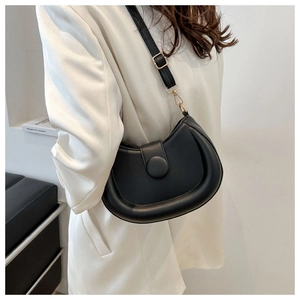 Detail of minimalist black crescent shoulder bag featuring a large round buckle and gold hardware