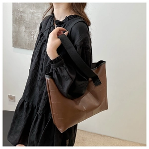 Brown patchwork leather tote bag with wide black strap shown on model in studio