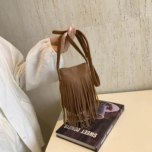 Brown vintage fringe bucket bag with long tassels and crossbody strap in hand-held view