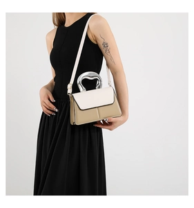 Détail du sac bandoulière bicolore avec poignée métallique argentée sur une robe noire