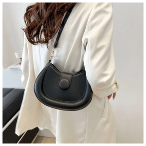 Detail of a black crescent shoulder bag with smooth finish and gold hardware on model