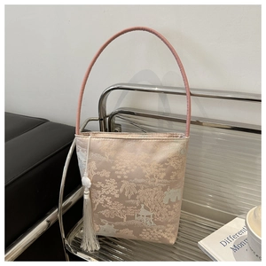Détail du sac seau en brocart rose avec broderie paysage et pompon de jade blanc