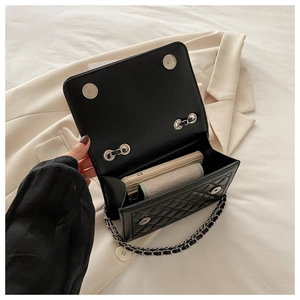 Interior view showing capacity of black quilted chain bag with magnetic flap closure
