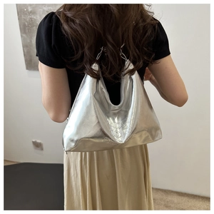 Détail du sac hobo argenté métallisé avec logo en relief et texture de qualité