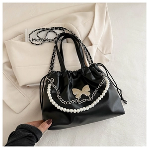 Detail of black drawstring bucket bag with pearl chain and silver butterfly ornament