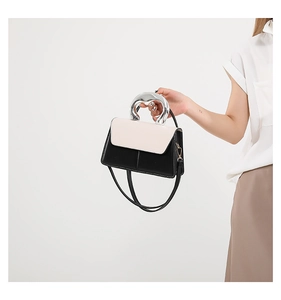 Détail du sac bandoulière en cuir avec une poignée incurvée en métal argenté