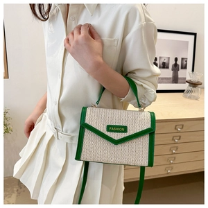 Vue détaillée du sac en paille avec bordure en cuir vert et plaque logo de mode pour femme
