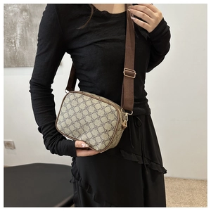 Détail d'un sac bandoulière beige à motif trèfle et large bandoulière en nylon marron
