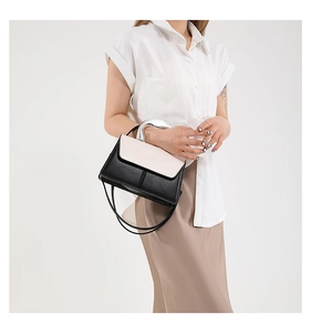 Détail d'un sac à main bicolore chic avec une poignée en métal argenté et une bandoulière