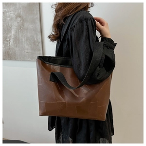 Side view of a brown tote bag with quilted pattern worn by a model in a minimalist room