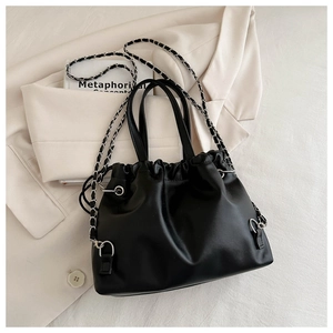 Close-up of black drawstring bucket bag with silver chain strap and pearl handle details