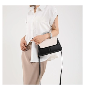 Close-up of contrast color handbag featuring silver metal handle and magnetic flap detail