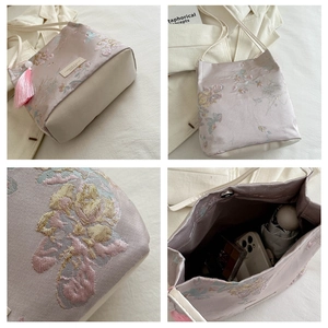 Macro detail of lavender satin bucket bag with floral embroidery and silk tassel charm