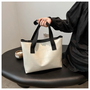Detail of off-white tote bag with geometric embossed texture and black wide strap