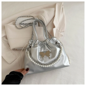 Close-up of metallic silver drawstring bucket bag with pearl handle and butterfly charm
