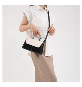 Detail of contrast color crossbody bag featuring silver metal handle and leather strap