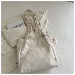 Detail der cremefarbenen Lackleder-Tasche mit geflochtenem Griff und buntem Seidentuch