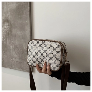 Détail d'un sac bandoulière vintage avec motif trèfle et crochets en métal doré