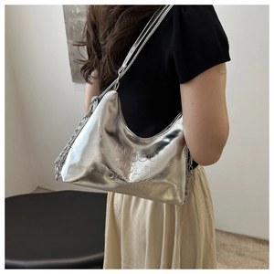 Close-up of silver tote bag with metallic chain strap and embossed designer lettering