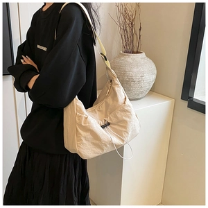 Detail of cream nylon crossbody bag featuring drawstring design and side zipper pocket
