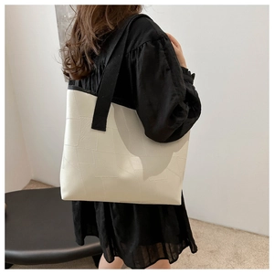 Detail of white tote bag with geometric texture and black fabric handles on model